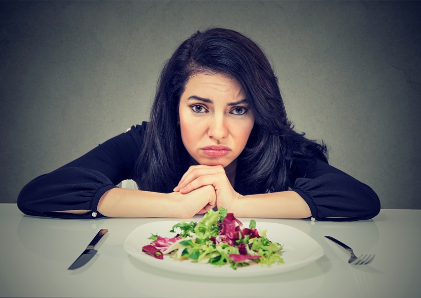 Foto ilustrativa de mulher tentando seguir dieta vegetariana com um prato de salada à frente - Metrópoles 