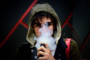 Jovem de capus usando cigarro eletrônico