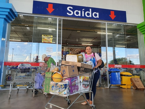 Consumidora saindo de supermercado com carrinho cheio