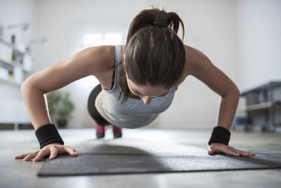 Mulher jovem fazendo flexão em casa