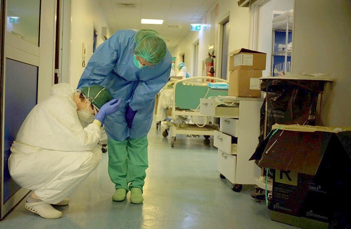 Profissional agachado, com a mão sobre a cabeça, sendo consolado por uma colega