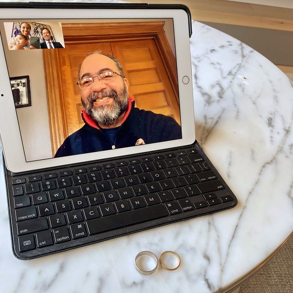 Juiz celebrando casamento pelo computador com alianças na mesa