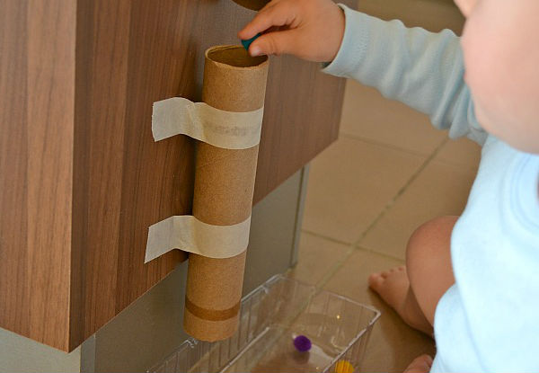 Criança brincando com tubo de papel higiênico em brincadeira inspirada no método montessoriano