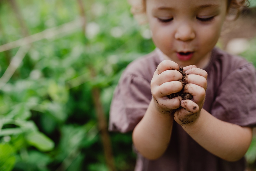 Criança com mãos sujas de terra