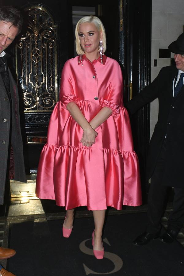 Katy Perry com vestindo rosa escondendo a gravidez com as maos