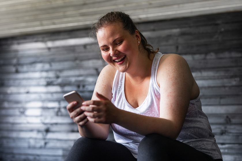 Mulher praticando exercícios com celular na mão