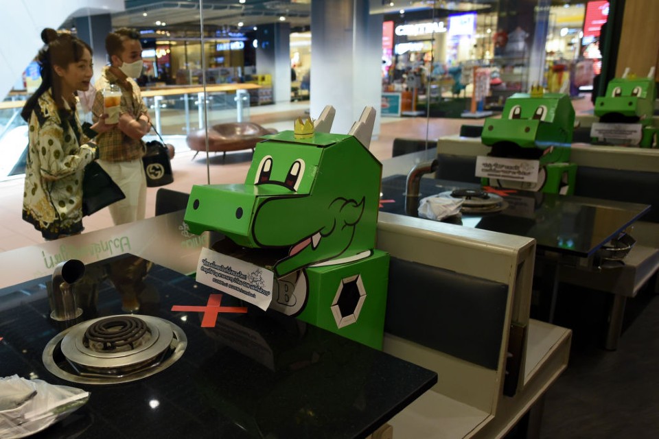 Dragões de papelão ocupam espaços em restaurante na Tailândia, para reforçar o distanciamento social