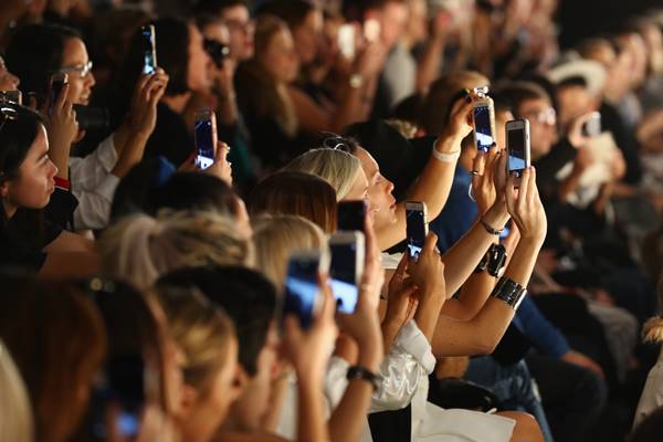 Pessoas com celulares em plateia de desfile de moda