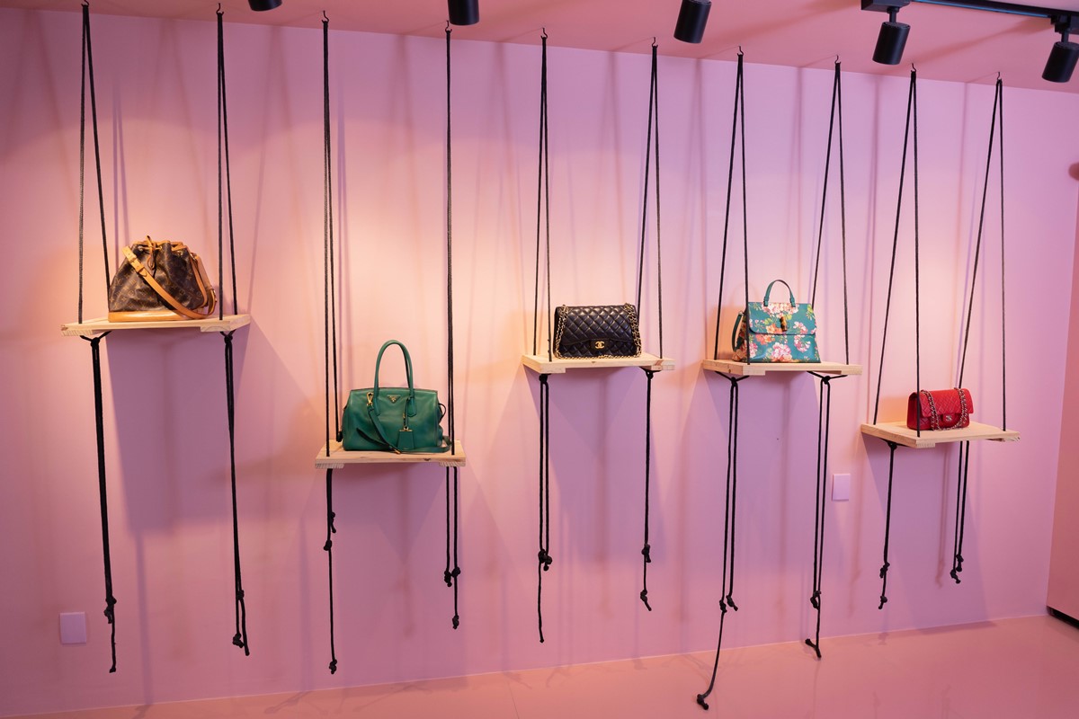 Showroom com bolsas de luxo em parede rosa