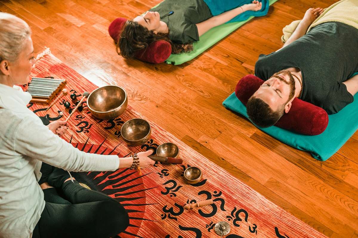 terapeuta tocando tigelas em sessão com duas pessoas