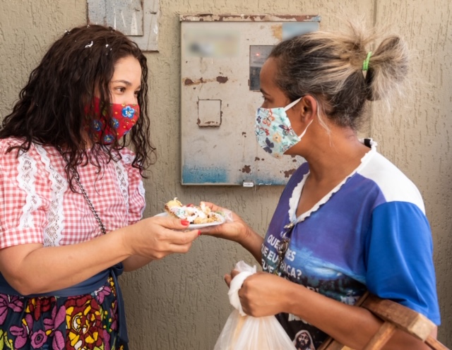 mulher entregando pedaço de bolo para outra mulher