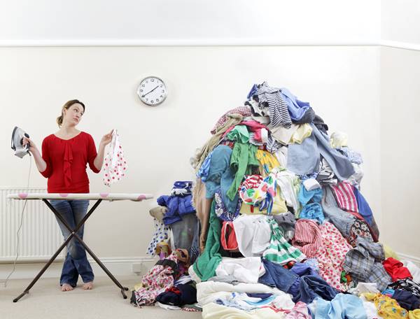 Mulher com pilha de roupas para passar