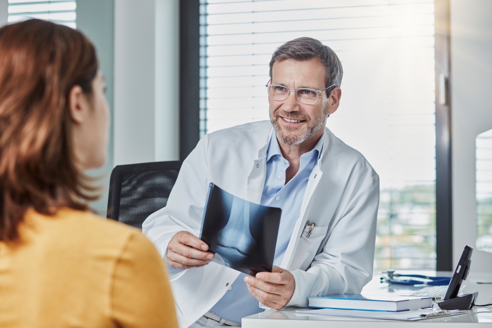 paciente conversa com médico ortopedista que segura exame de raio x