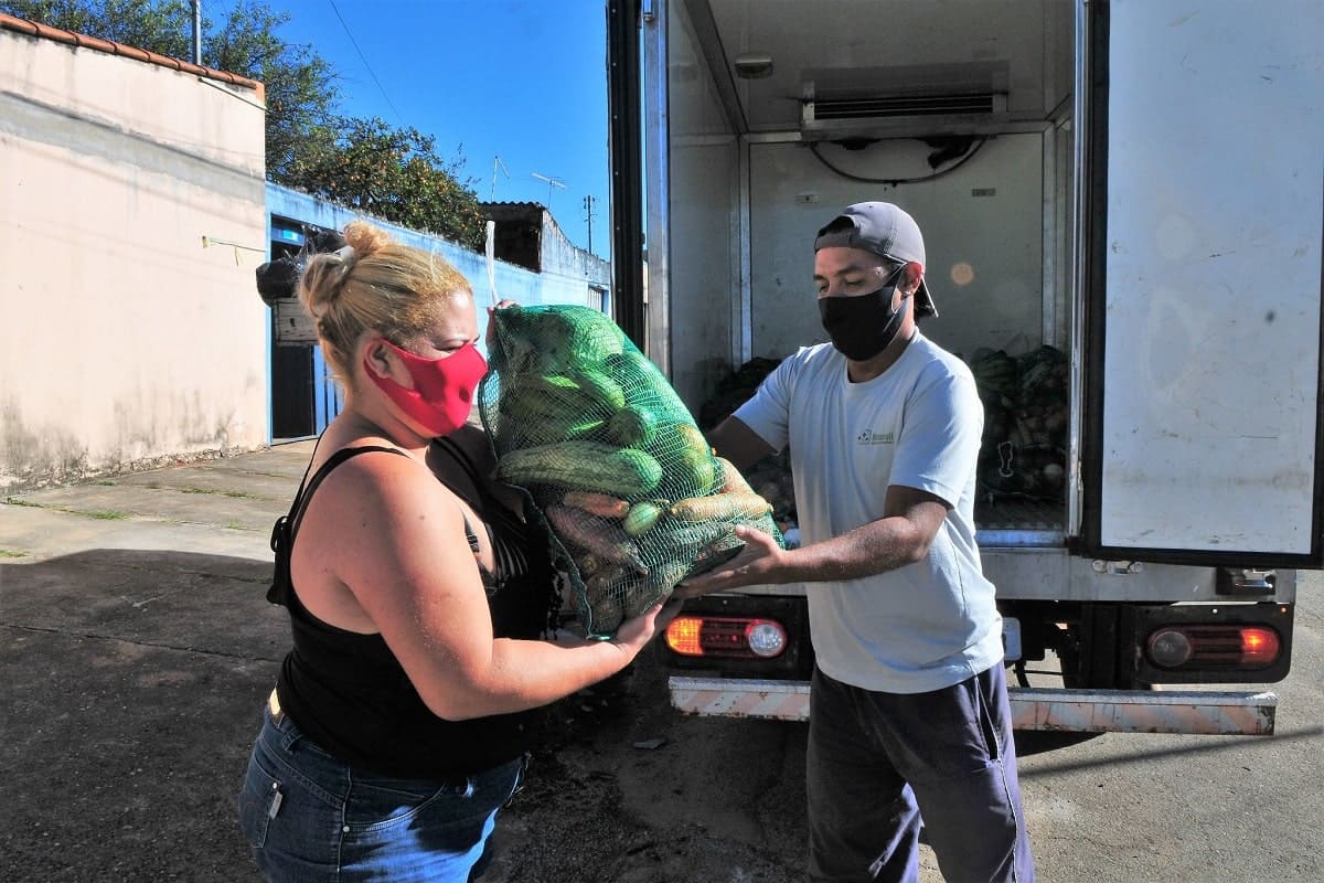 mulher recebe cesta de alimentos usando mascara de proteção contra a covid-19