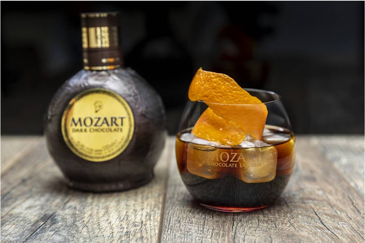 Drinque Old Fashioned com chocolate ao lado de uma garrafa de licor Mozart