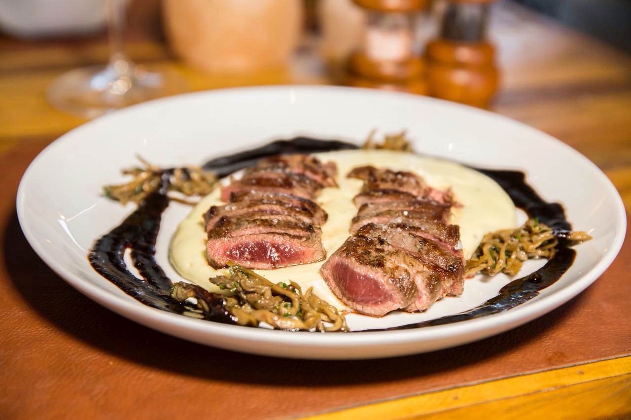 Aligot com lombo de cordeiro, molho de jabuticaba e shimeji, um dos pratos mais pedidos do Sal Gastronomia