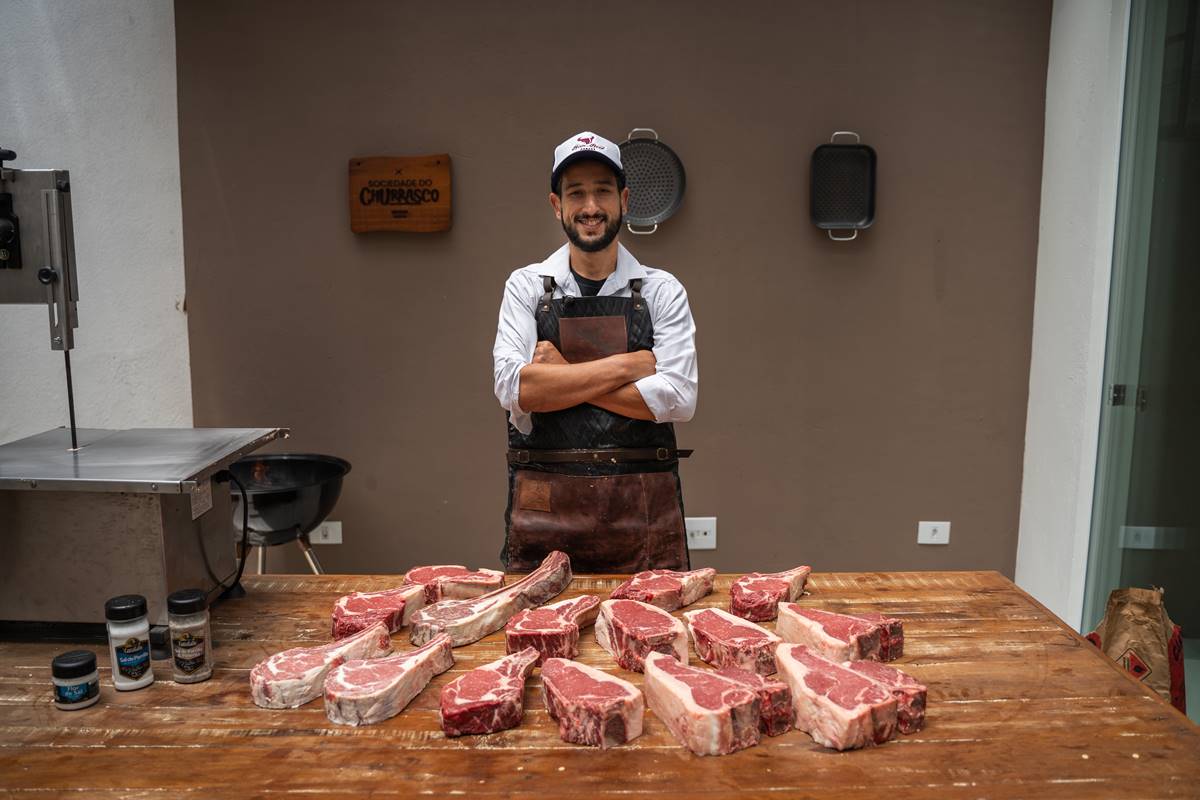 Netão Bom Beef com faca e chaira na mão e cortes de carne sobre a mesa