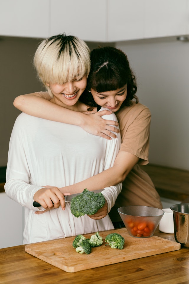 casal de mulheres se abraçando e cozinhando