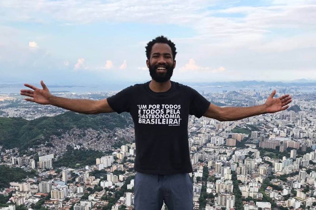 Chef João Diamante posa de braços abertos em alto do morro