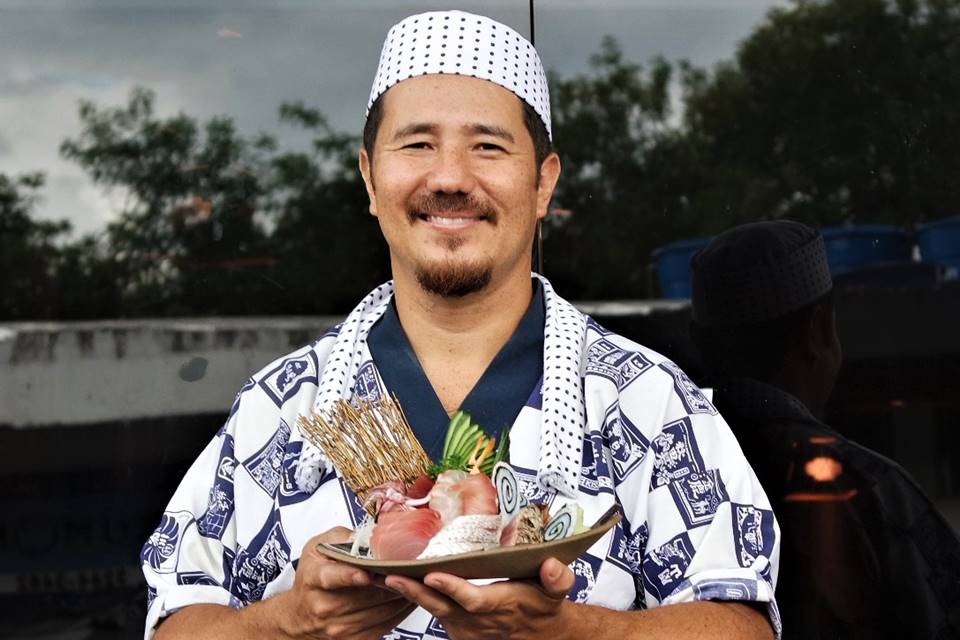 Foto colorida de um homem segurando um prato com sushis - Metrópoles