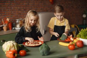 Crianças cozinhando um prato com muitos vegetais