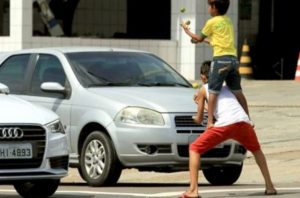 duas crianças fazendo malabarismo em frente a carros