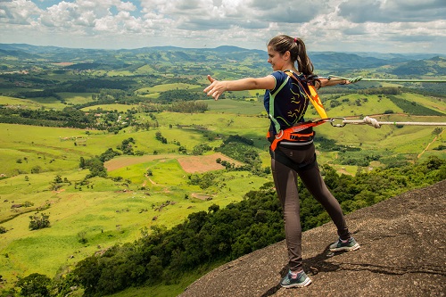 mulher em cima de mirante com vista para cadeia de montanhas