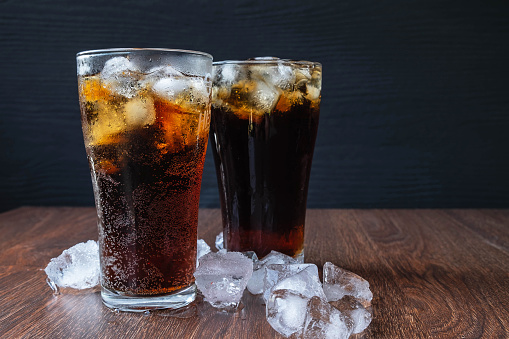 coca-cola cercada de gelo em plano de fundo escuro