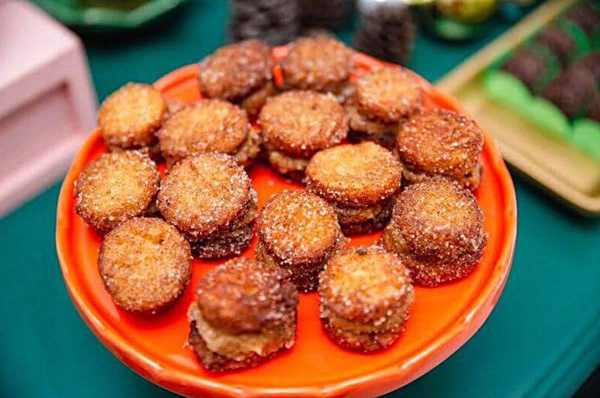 Na foto vemos um prato laranja com várias mini rabanadas. São circulos de pão frito na cor caramelo com cristais de açúcar