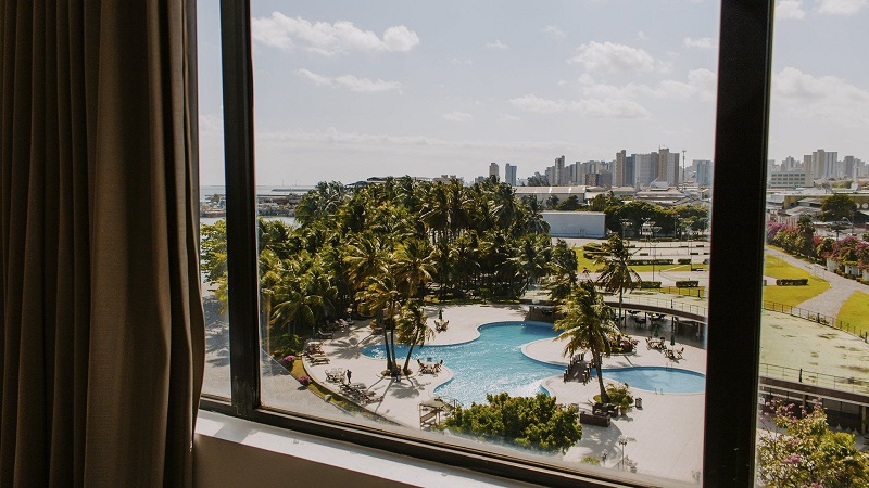 vista de janela com piscina e mar