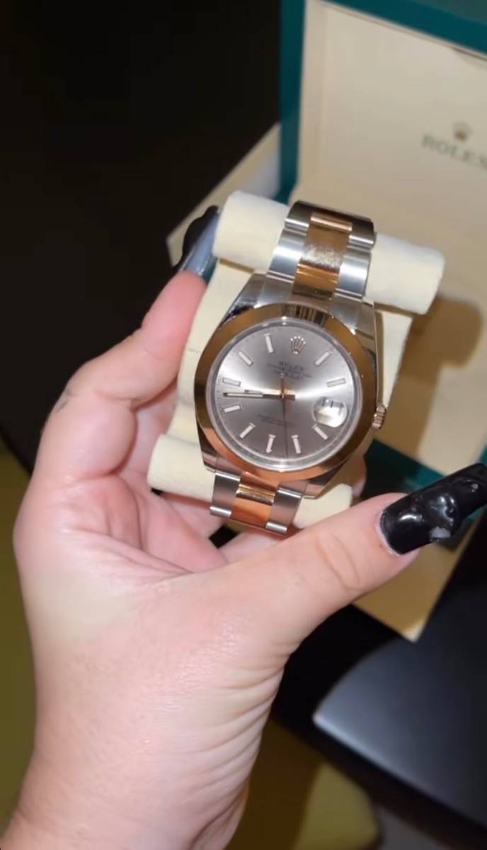 Foto de uma mão feminina segurando um Rolex dourado