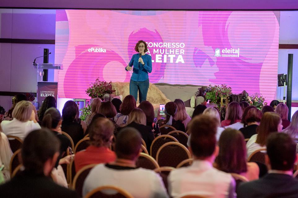 Mulher em um palco com pessoas ao fundo 