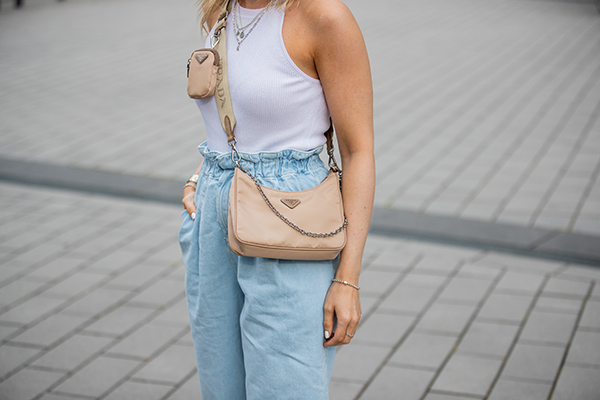 Mulher branca com bolsa bege da marca Prada