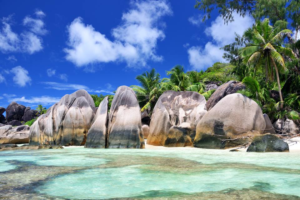 Praia de águas cristalinas com paredões rochosos ao lado