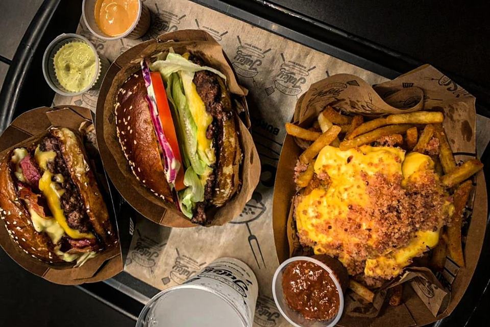 na foto temos dois hamburgueres e uma porção de batatas fritas cobertas de queijo cheddar