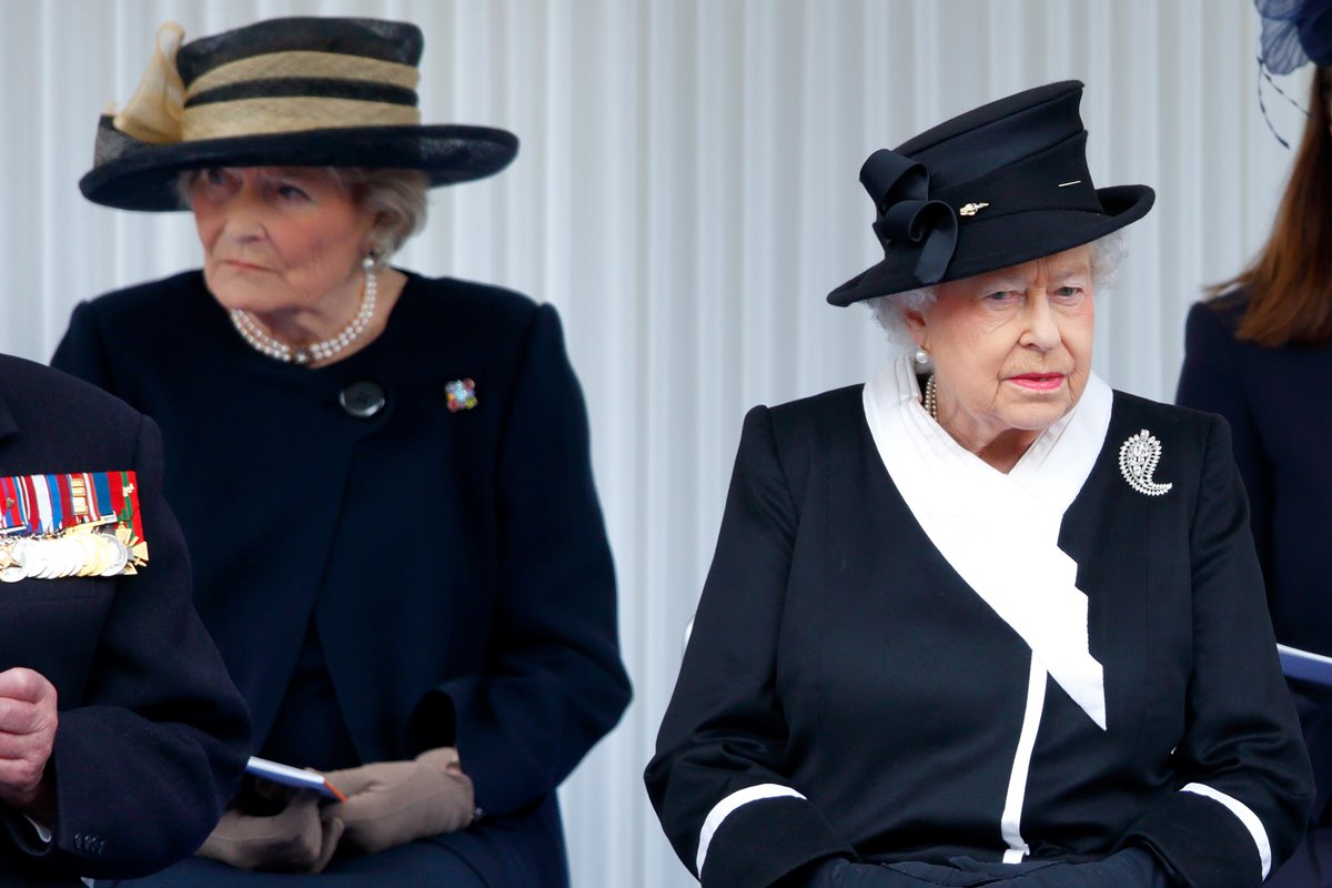 Duas mulheres sentadas lado a lado. Elas vestem roupas na cor pretas 