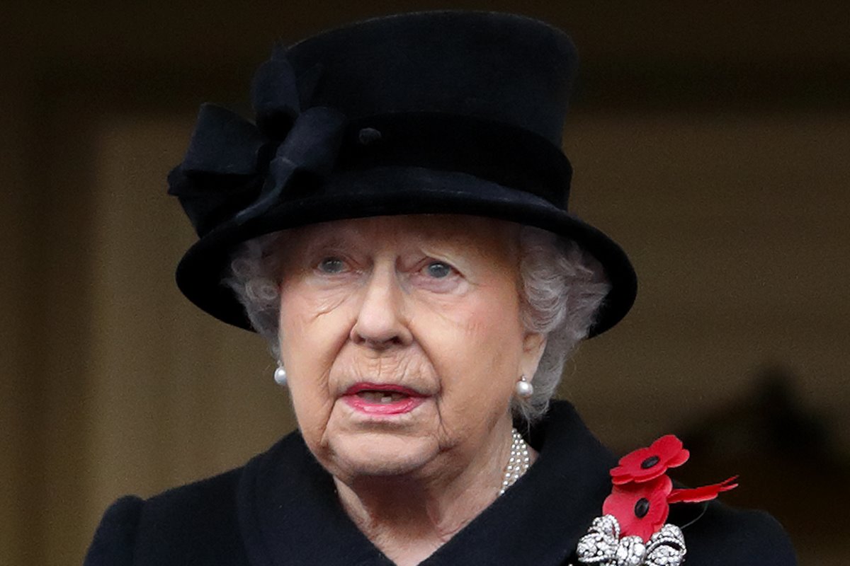 Mulher idosa chorando. Ela veste roupas pretas e usa um broche com flores vermelhas