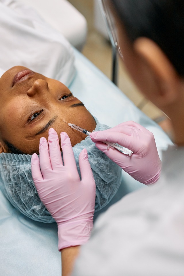 Médica aplicando injeção na testa de paciente mulher