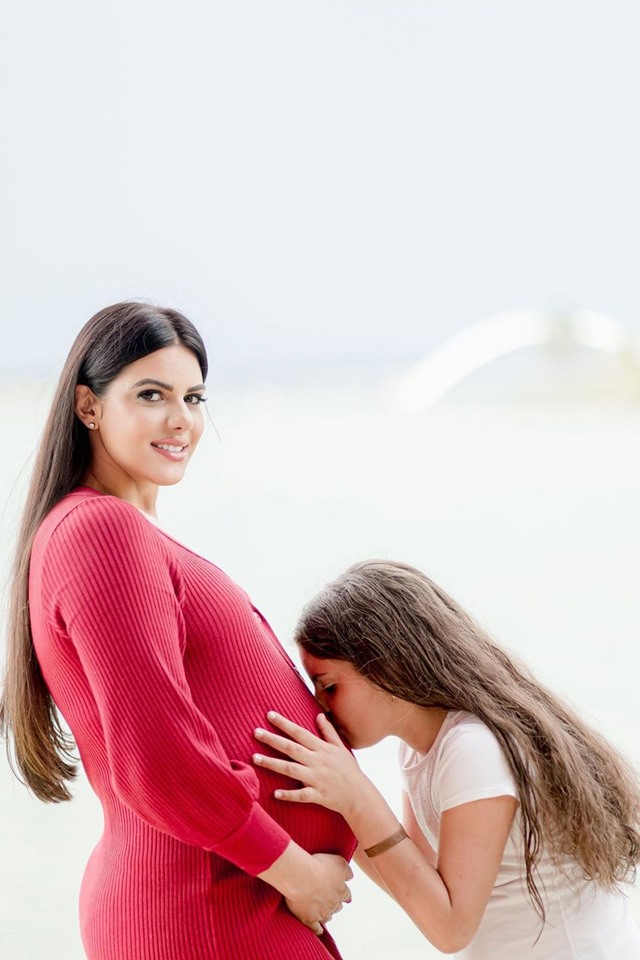 Menina beija a barriga de mulher gestante