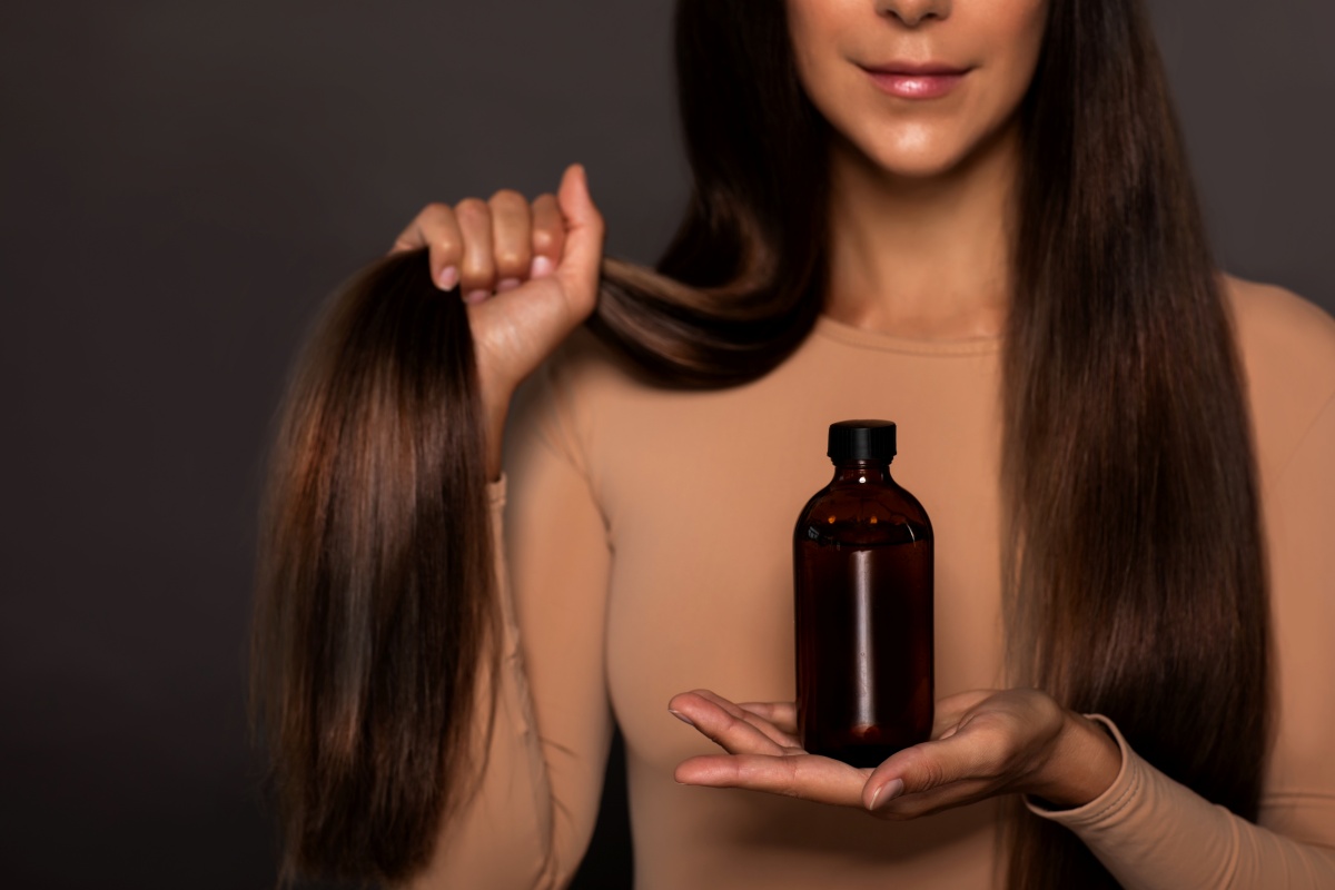 Mulher segurando o cabelo e um frasco de vidro