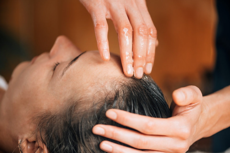 Mãos aplicando produto em cabelo de cliente