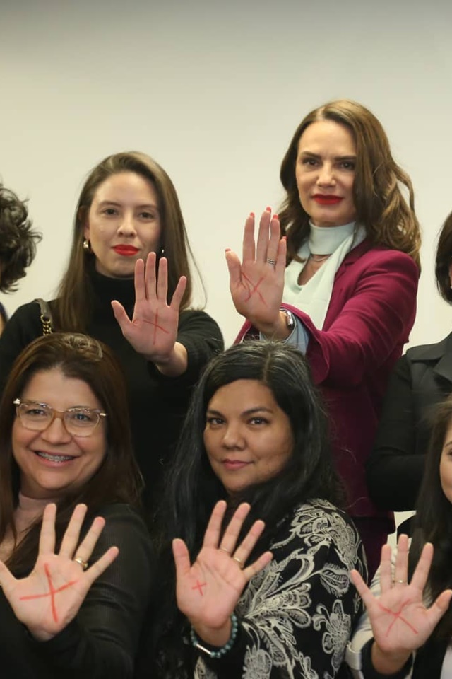 Mulheres com a letra X nas mãos. O símbolo foi feito com batom