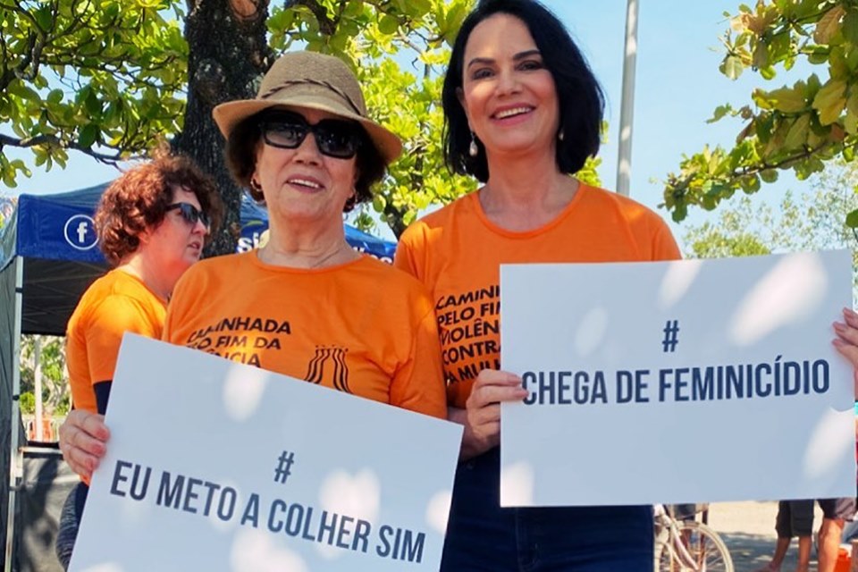 Mulheres com cartazes e blusas na cor laranja