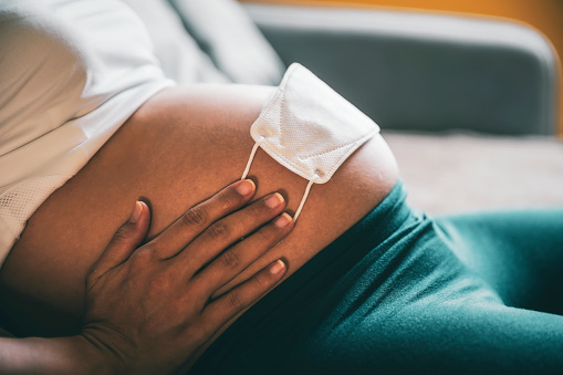 Grávida com uma máscara na barriga