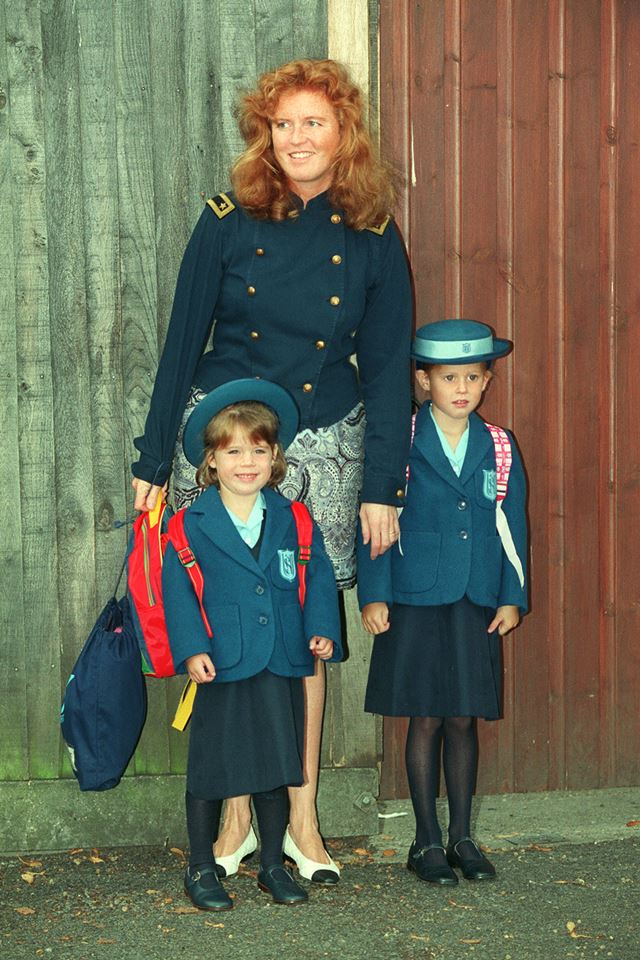 Mulher ruiva acompanhada de duas meninas vestidas com uniformes verdes