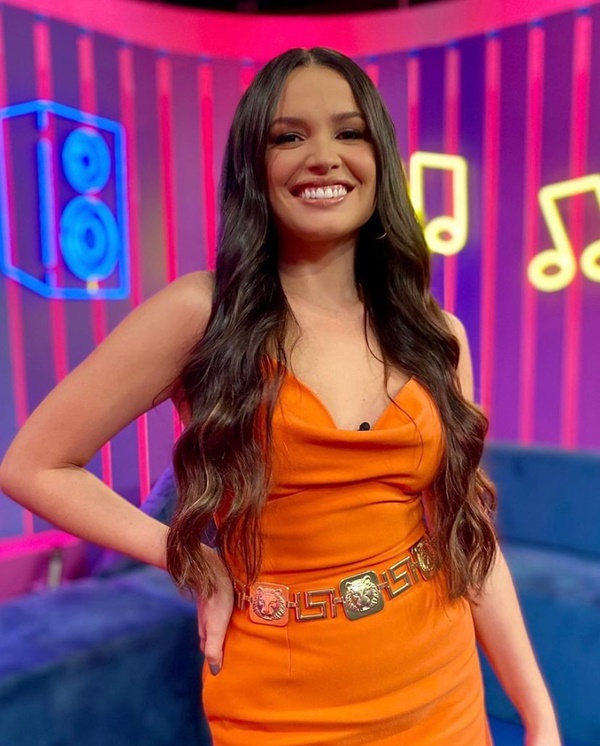 Ex-BBB Juliette com vestido laranja e cinto dourado no programa do Multishow