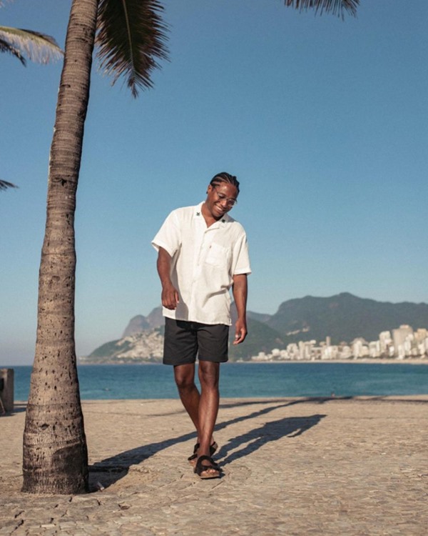 Modelo negro em praia do Rio de Janeiro com bermuda jeans preta e camisa branca da Levi's