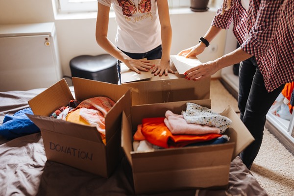 Pessoas organizando roupas em caixas de papelão para doar