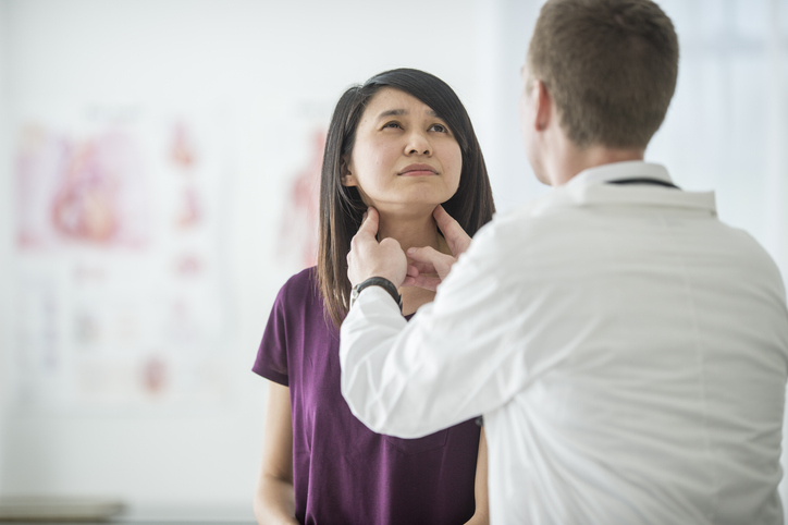 Mulher se consulta com médico que examina o seu pescoço. Ela está sentada de frente para ele e olha para cima, com incômodo no rosto-Metrópoles