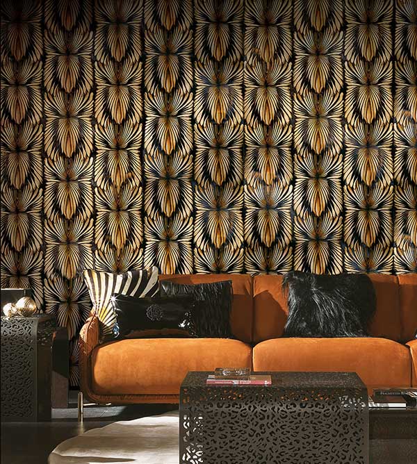 Sofá marrom e uma sala com papel de parede preto e dourado. Sob o sofá., almofadas pretas de pelo e outra com estampa de zebra. Todas as peças são da linha de decoração da Roberto Cavalli